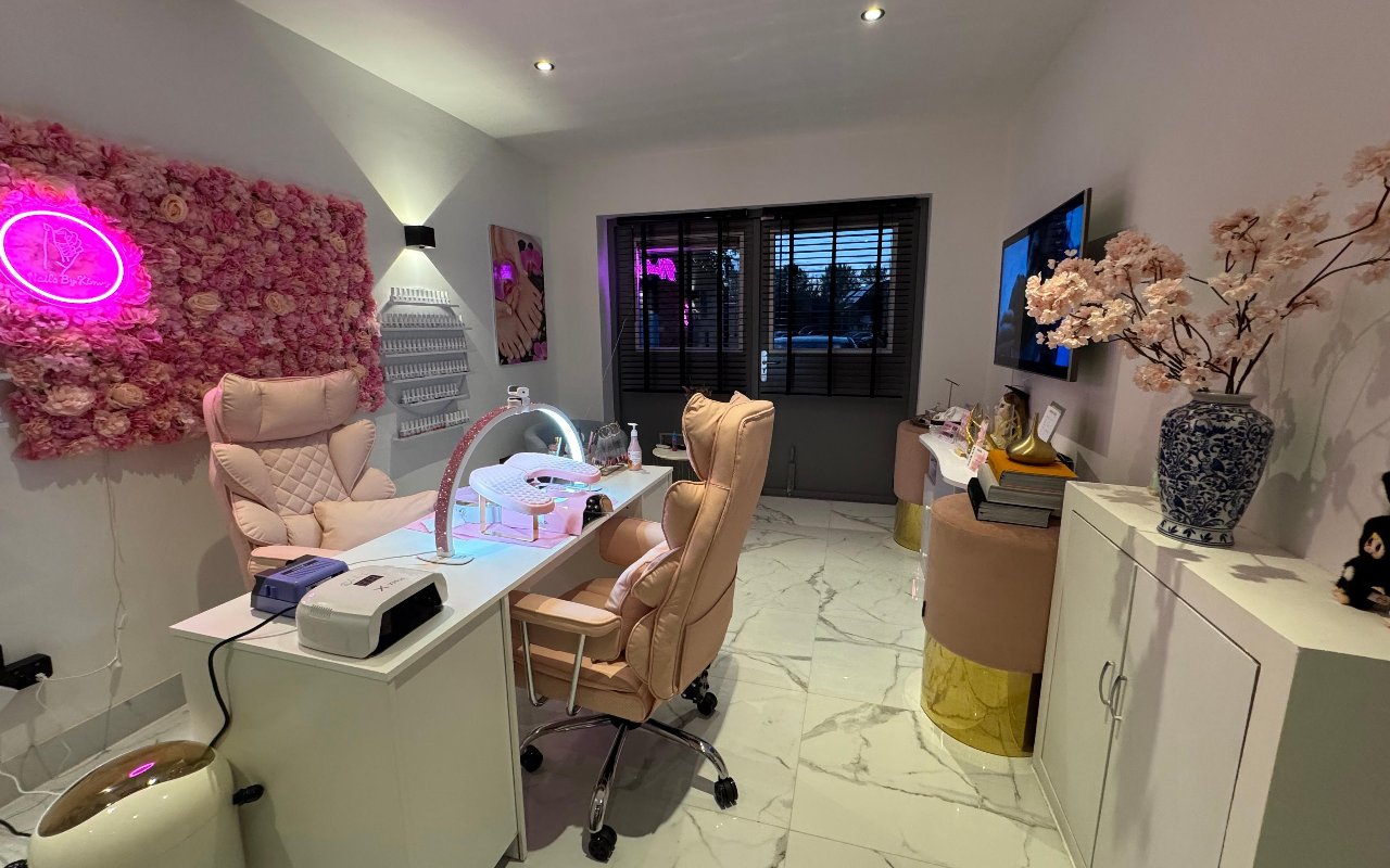 De salon van Nails By KimVy met de roze bloemenwand en de neon ring